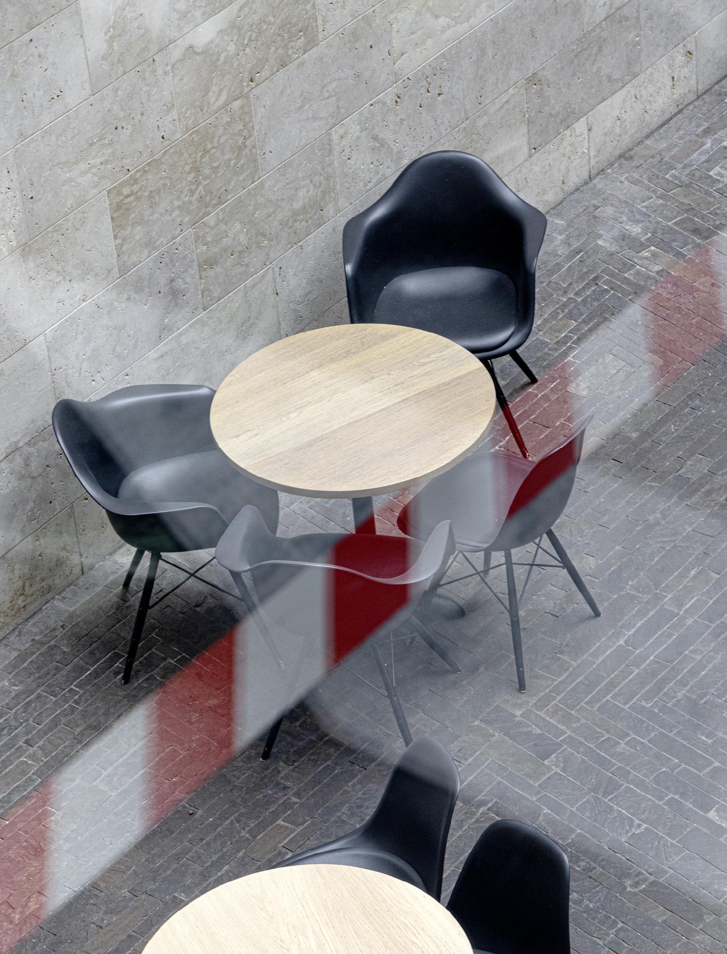 Blick auf einen Tisch eines Kaffees durch eine Glasscheibe hindurch, in der sich ein Absperrband spiegelt